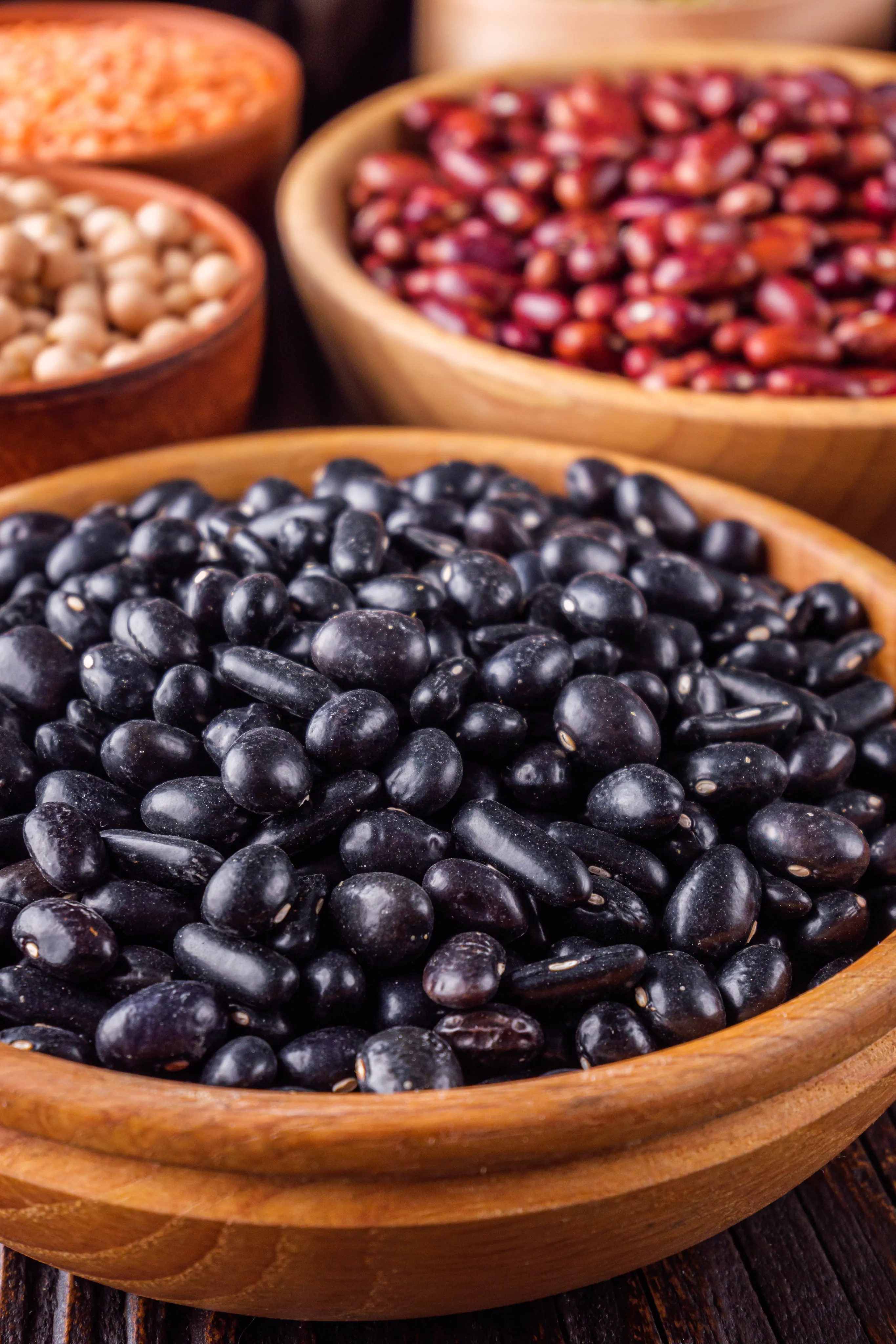 Frijol negro y otros granos en cuencos de madera